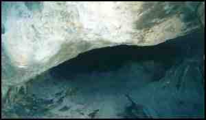 The entrance to a cave in rock where a stream disappears into the ground