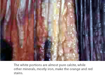 The white portions are almost pure calcite, while other minerals, mostly iron, make the orange and red stains.